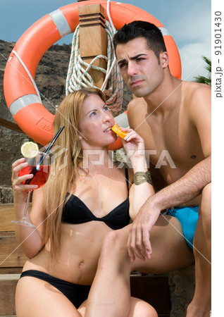 couple having a cocktail by the pool while enjoying the sun in spring or summer couple having a cocktail by the pool while enjoying the sun in spring or summer 91901430