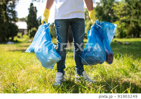 Close up of a person with bags with garbage in hands Close up of a person with bags with garbage in hands 91903249