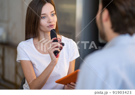 Pretty young journalist interviewing a famous person in a studio 91903423
