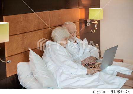Two seniors watching something on laptop and looking interested Two seniors watching something on laptop and looking interested 91903438
