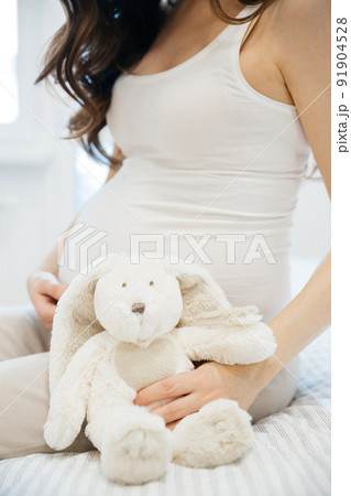 Pregnancy, motherhood, people and expectation concept - close up of happy pregnant woman with big belly on white background. Beautiful pregnant woman sitting on bed expecting child. Postcard, banner. 91904528