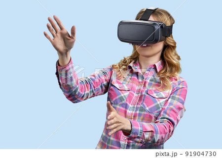 Excited young woman using virtual reality glasses on color background. 91904730