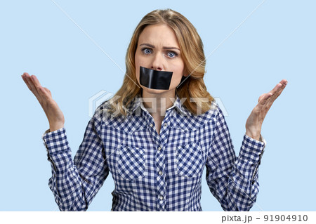 Female protestor with black tape over her mouth demonstrating protest standing on color background. Female protestor with black tape over her mouth demonstrating protest standing on color background. 91904910
