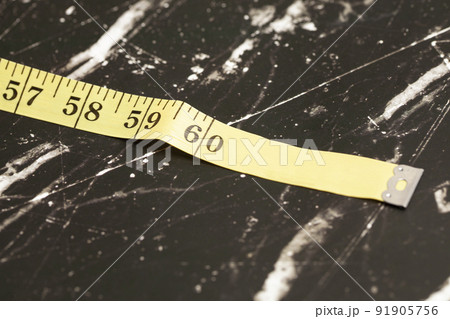 Yellow measuring tape on a dark background. Yellow measuring tape on a dark background. 91905756