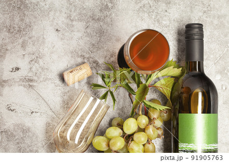 White wine bottle with bunch of grapes, glass on a marble background, top view. White wine bottle with bunch of grapes, glass on a marble background, top view. 91905763
