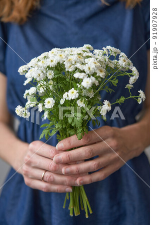 Bouquet of white wildflowers in the hands of a midsection woman in a Bouquet of white wildflowers in the hands of a midsection woman in a 91907928