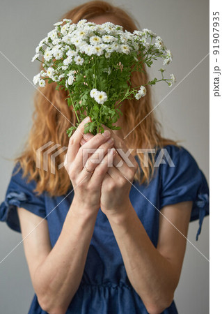 faceless red-haired woman in a blue dress covers her face with white faceless red-haired woman in a blue dress covers her face with white 91907935