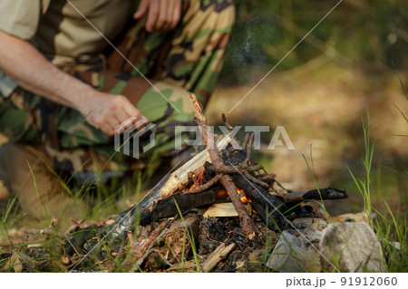 Man is making campfire in the woods. The concept of adventure, travel, tourism, camping, survival and evacuation. 91912060