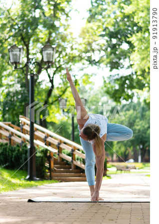 Young man practice yoga in the park. Yoga asanas in city park, sunny day. Concept of meditation, wellbeing and healthy lifestyle 91913790
