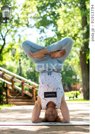 Young man practice yoga in the park. Yoga asanas in city park, sunny day. Concept of meditation, wellbeing and healthy lifestyle Young man practice yoga in the park. Yoga asanas in city park, sunny day. Concept of meditation, wellbeing and healthy lifestyle 91913794