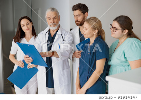 Doctor giving lecture to interns in hospital discussing patient diagnosis 91914147