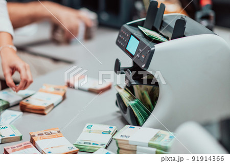 Bank employees using money counting machine while sorting and counting paper banknotes inside bank vault. Large amounts of money in the bank Bank employees using money counting machine while sorting and counting paper banknotes inside bank vault. Large amounts of money in the bank 91914366