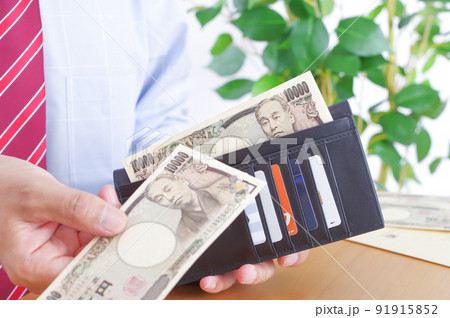 財布から一万円札を出すワイシャツ姿の男性 91915852