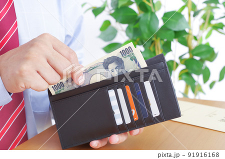 財布から千円札を出すワイシャツ姿の男性 91916168