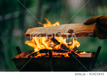 焚き火に燃料(薪)を追加する男性キャンパー(キャンプ) 焚き火に燃料(薪)を追加する男性キャンパー(キャンプ) 91922643