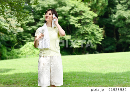 木陰で扇風機を使う女性 91923982