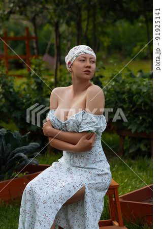Sensitive woman sitting near garden beds 91925141