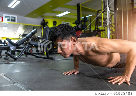 Young athletic man doing push-ups. Muscular and strong guy exercising. Young athletic man doing push-ups. Muscular and strong guy exercising. 91925403