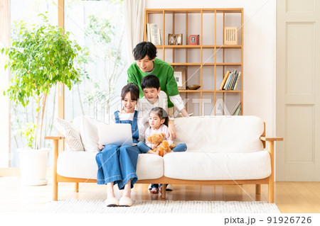 リビングでパソコンを見る若い家族 91926726