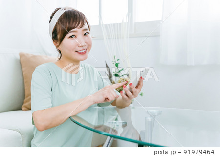 家でスマホを使う笑顔の日本人女性（アプリ） 91929464