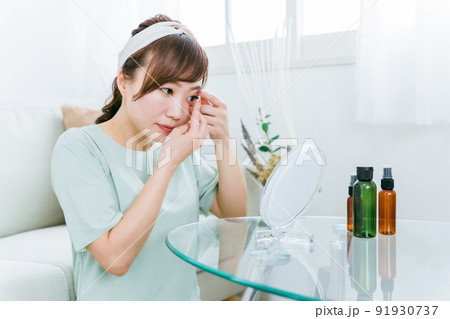 家でコンタクトレンズをつける女性 91930737
