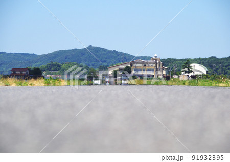 夏の炎天下のアスファルト路面の遠くで風景が陽炎に揺らいでいる光景 91932395