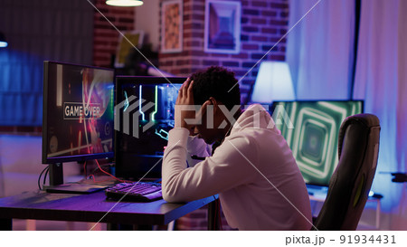 African american man shouting angry after losing online tournament streaming multiplayer first person shooter on gaming pc. Gamer playing internet action game upset after failing level. 91934431