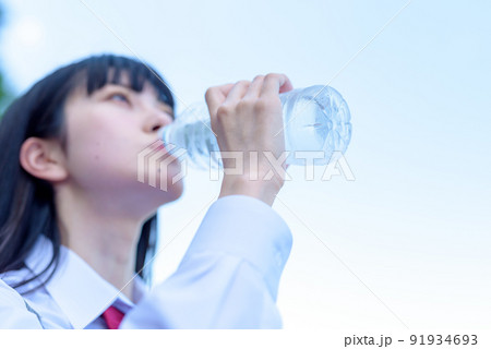 外でペットボトルの水を飲む女子高校生　ミネラルウォーター　美容　健康習慣　熱中症予防　ピント手元 91934693