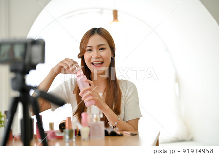 Beautiful talented millennial Asian female beauty blogger recording makeup tutorial video Beautiful talented millennial Asian female beauty blogger recording makeup tutorial video 91934958