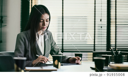Pensive professional financial advisor working with statistics document at her office Pensive professional financial advisor working with statistics document at her office 91935008
