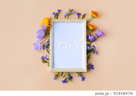 Blue bluebell, lobelia flowers and orange calendula flowers with a white text frame on an orange background. Summer flat lay 91938479