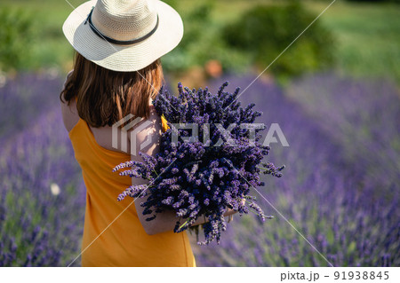 Girl in a yellow dress and a straw hat with a huge bouquet of lavender flowers. Girl in a yellow dress and a straw hat with a huge bouquet of lavender flowers. 91938845