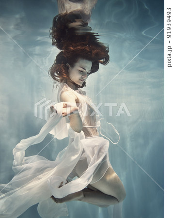 A girl in a white dress with lace swims underwater as if flying 91939493