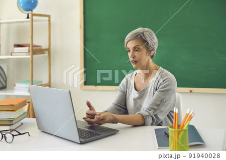 Online learning education. Female senior teacher is teaching students or schoolchildren using a video conference has a laptop in the classroom. Online learning education. Female senior teacher is teaching students or schoolchildren using a video conference has a laptop in the classroom. 91940028