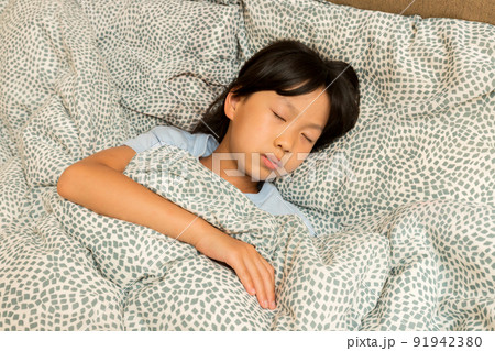 暖かい布団の中で寝ている小学生の女の子の様子 暖かい布団の中で寝ている小学生の女の子の様子 91942380