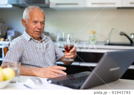 Senior man with glass of brandy and laptop 91943793