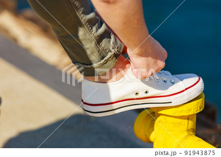 Woman tying laces in sneakers outdoors 91943875