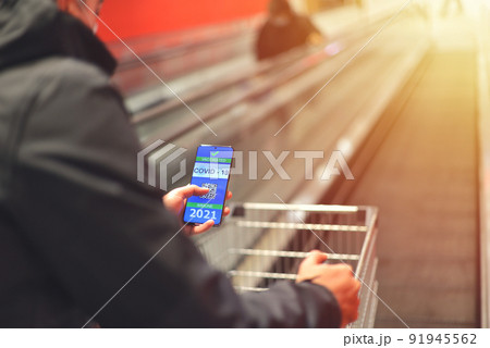 Covid-19 Health Passport in shopping center. Vaccinated man holding cell phone with covid 19 vaccination proof 91945562