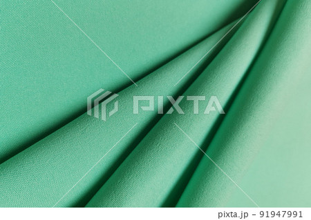 Green crumpled or wavy fabric texture background. Abstract linen cloth soft waves. Gabardine wool fabric. Merino yarn. Smooth elegant luxury cloth texture. Concept for banner or advertisement. 91947991