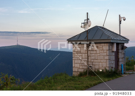 Upper water reservoir of the pumped storage hydro power plant Dlouhe Strane in Jeseniky Mountains, Czech Republic. Top of the Praded mountain behind the lake. During summer evening, sunset. Upper water reservoir of the pumped storage hydro power plant Dlouhe Strane in Jeseniky Mountains, Czech Republic. Top of the Praded mountain behind the lake. During summer evening, sunset. 91948033
