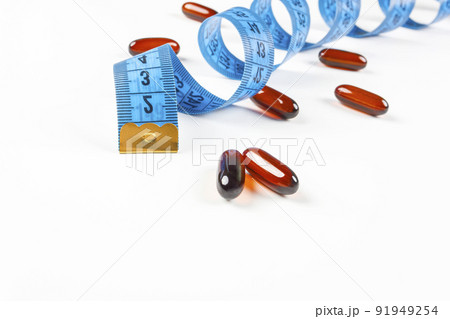 Pile of leptin capsules with blue measuring tape on white background. Concept of losing weight, diet, fat burning, healthy eating. Pile of leptin capsules with blue measuring tape on white background. Concept of losing weight, diet, fat burning, healthy eating. 91949254