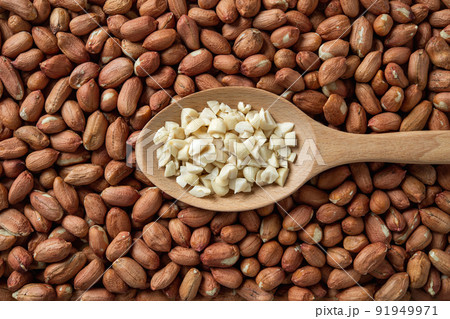 Crushed peanut in a wooden spoon over whole groundnut seeds. Crushed peanut in a wooden spoon over whole groundnut seeds. 91949971