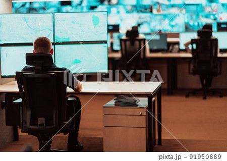 Male security operator working in a data system control room offices Technical Operator Working at workstation with multiple displays, security guard working on multiple monitors Male computer opera 91950889
