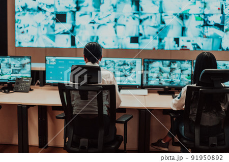 Group of Security data center operators working in a CCTV monitoring room looking on multiple monitors Officers Monitoring Multiple Screens for Suspicious Activities Team working on the System Contr 91950892