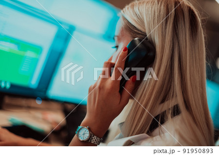Female security guard operator talking on the phone while working at workstation with multiple displays Security guards working on multiple monitors 91950893