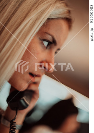 Female security guard operator talking on the phone while working at workstation with multiple displays Security guards working on multiple monitors Female security guard operator talking on the phone while working at workstation with multiple displays Security guards working on multiple monitors 91950988