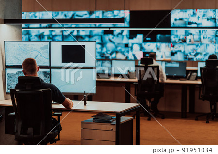 Male security operator working in a data system control room offices Technical Operator Working at workstation with multiple displays, security guard working on multiple monitors Male computer opera Male security operator working in a data system control room offices Technical Operator Working at workstation with multiple displays, security guard working on multiple monitors Male computer opera 91951034