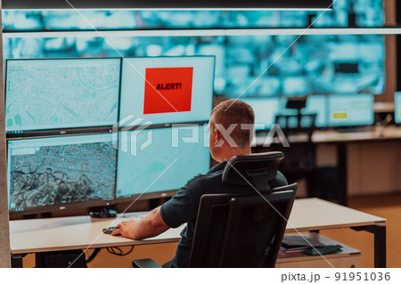 Male security operator working in a data system control room offices Technical Operator Working at workstation with multiple displays, security guard working on multiple monitors Male computer opera Male security operator working in a data system control room offices Technical Operator Working at workstation with multiple displays, security guard working on multiple monitors Male computer opera 91951036