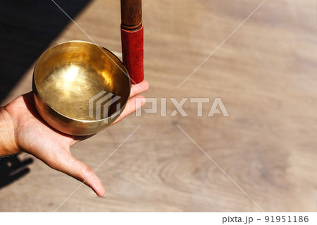Man hands using singing bowl in sound healing therapy outdoors, closeup. 91951186