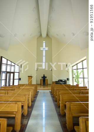 Long aisle between two rows of wooden benches leading towards priest Long aisle between two rows of wooden benches leading towards priest 91951566